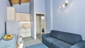 A compact living space with a kitchenette, a sofa, and a dining table with fruit. - Nice apartment on the ground floor with sea view of about 45 m2 equipped with air conditioning and wi fi connection, composed of a living room with equipped kitchenette, fridge and flat-screen television.It can be on one level or with a mezzanineA double (Bosa Marina)