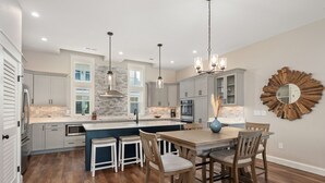 A modern kitchen with a central island, pendant lighting, and a rustic mirror. - Casita Miramar!: Semi-Oceanfront, Newly-Built Townhome, Community Pool! (Kill Devil Hills)