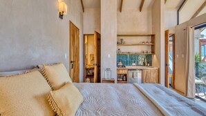 Una camera da letto con un letto grande, una porta in legno, un bagno piccolo e un angolo cottura.
