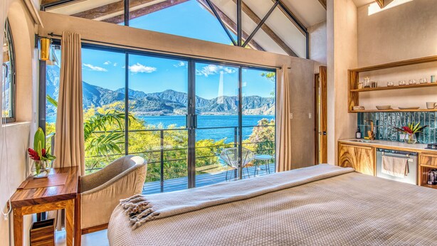 Una camera da letto con un'ampia finestra che offre una vista panoramica su montagne e un lago.