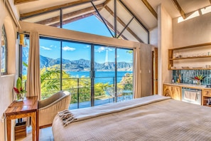 A bedroom with a large window offering a scenic view of mountains and a lake. - Tierra de la Aurora (San Marcos La Laguna)