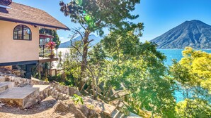 Una casa con una scala in pietra che conduce a un balcone, con vista su un corpo d'acqua e una montagna.
