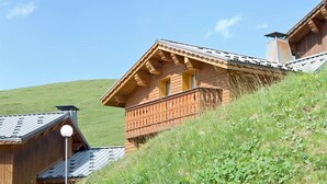 A wooden chalet with a balcony, set on a hillside with a clear sky. - Chalet privé et sympa 7p, ski aux pieds (Macot-la-Plagne)