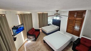 Quarto de hotel com televisão, duas camas, sofá e guarda-roupa.