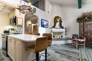 A kitchen with a central island, bar stools, a fireplace with candles, and a decorative wreath. - Euro-Inspired Vail Village Condo, Walk to Ski Lift (Vail)