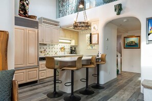 Cozinha com ilha central, banquetas e lustre.