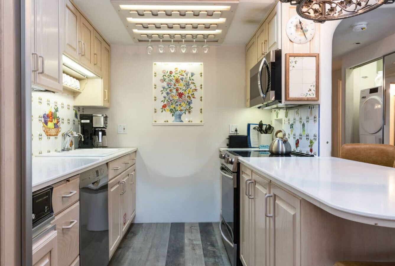 Une cuisine compacte équipée d’un four à micro-ondes, d’une cuisinière et d’un évier. Un élément décoratif orne le mur au-dessus du plan de travail.