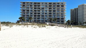 A multi-story hotel with balconies, located on a sandy beach with palm trees. - Beachside @ Seaside Beach & Racquet 2BR Condo • Sleeps 6 • Pools, Tennis & Beach Access (Orange Beach)