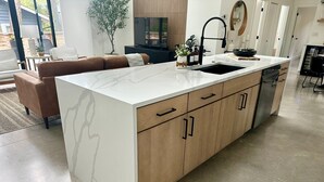 Une cuisine moderne avec un plan de travail en marbre blanc, des armoires en bois et un robinet noir.