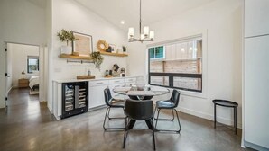 Une cuisine moderne avec un îlot central, des chaises noires et un lustre.