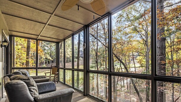A modern room with large windows, a leather sofa, and a ceiling fan.