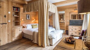Een houten slaapkamer met een hemelbed, houten planken en een klein tafeltje met een mand.