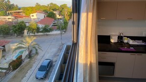 Un balcón con vistas a una calle residencial, un coche y una piscina.
