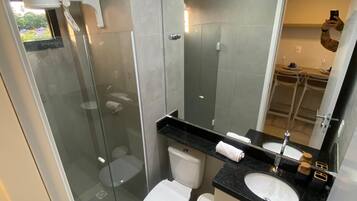 Moderni kylpyhuone, jossa on lasinen suihkuseinä, wc-istuin, peilillä varustettu pesuallas sekä allaskaappi.