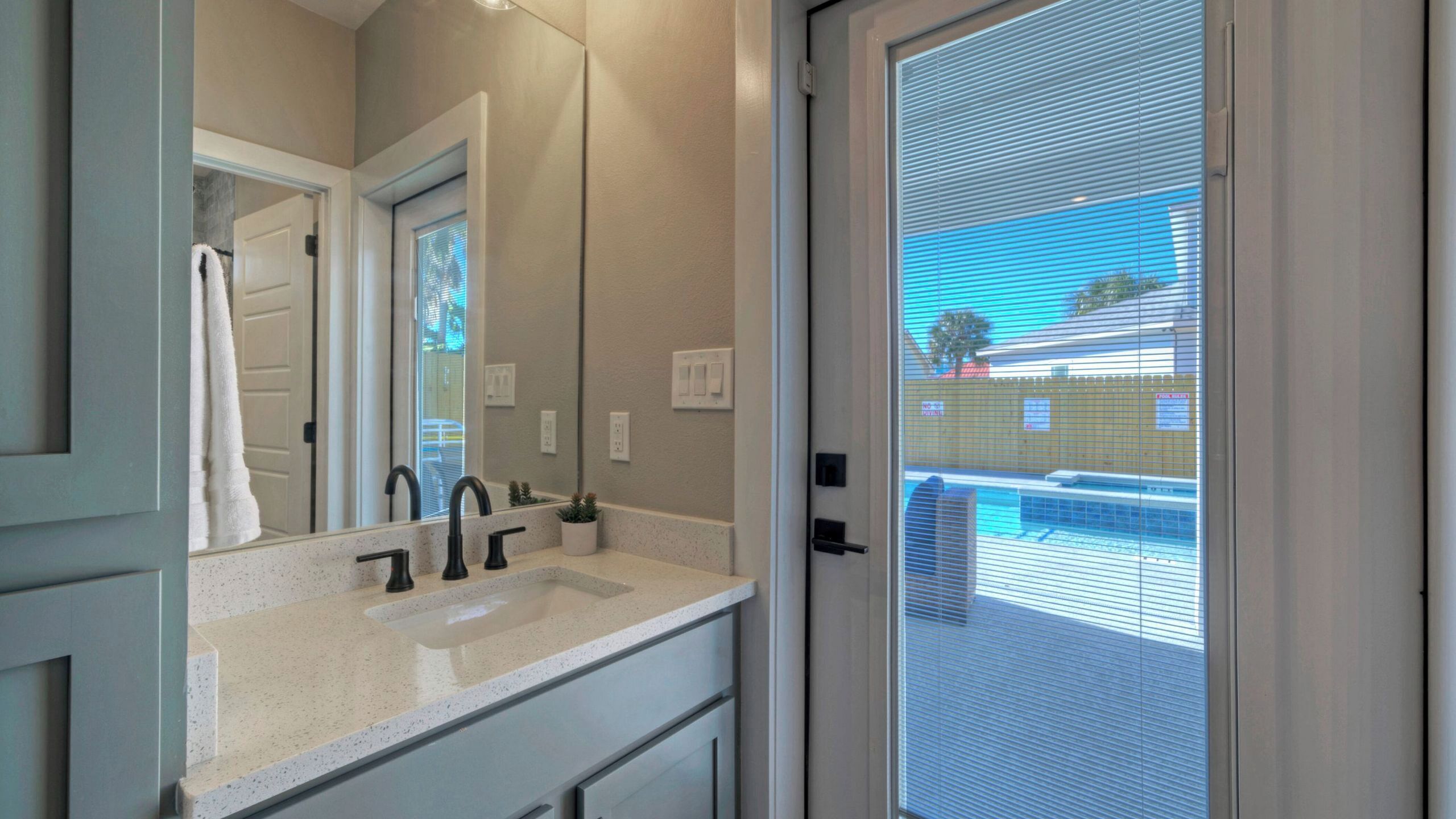 A bathroom with a sink, mirror, and window.
