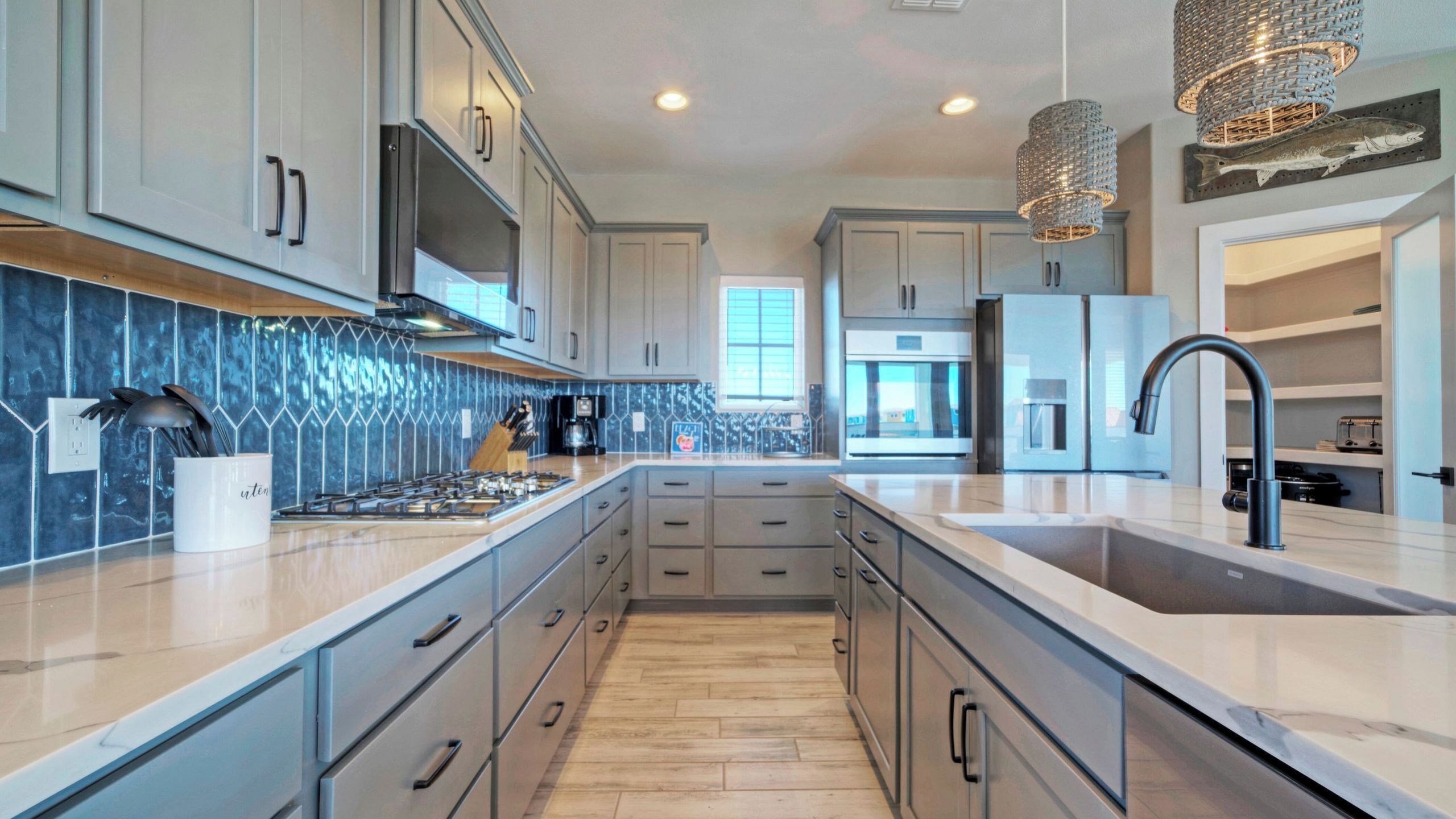 A modern kitchen with a central island, stainless steel appliances, and a decorative fish wall art piece.