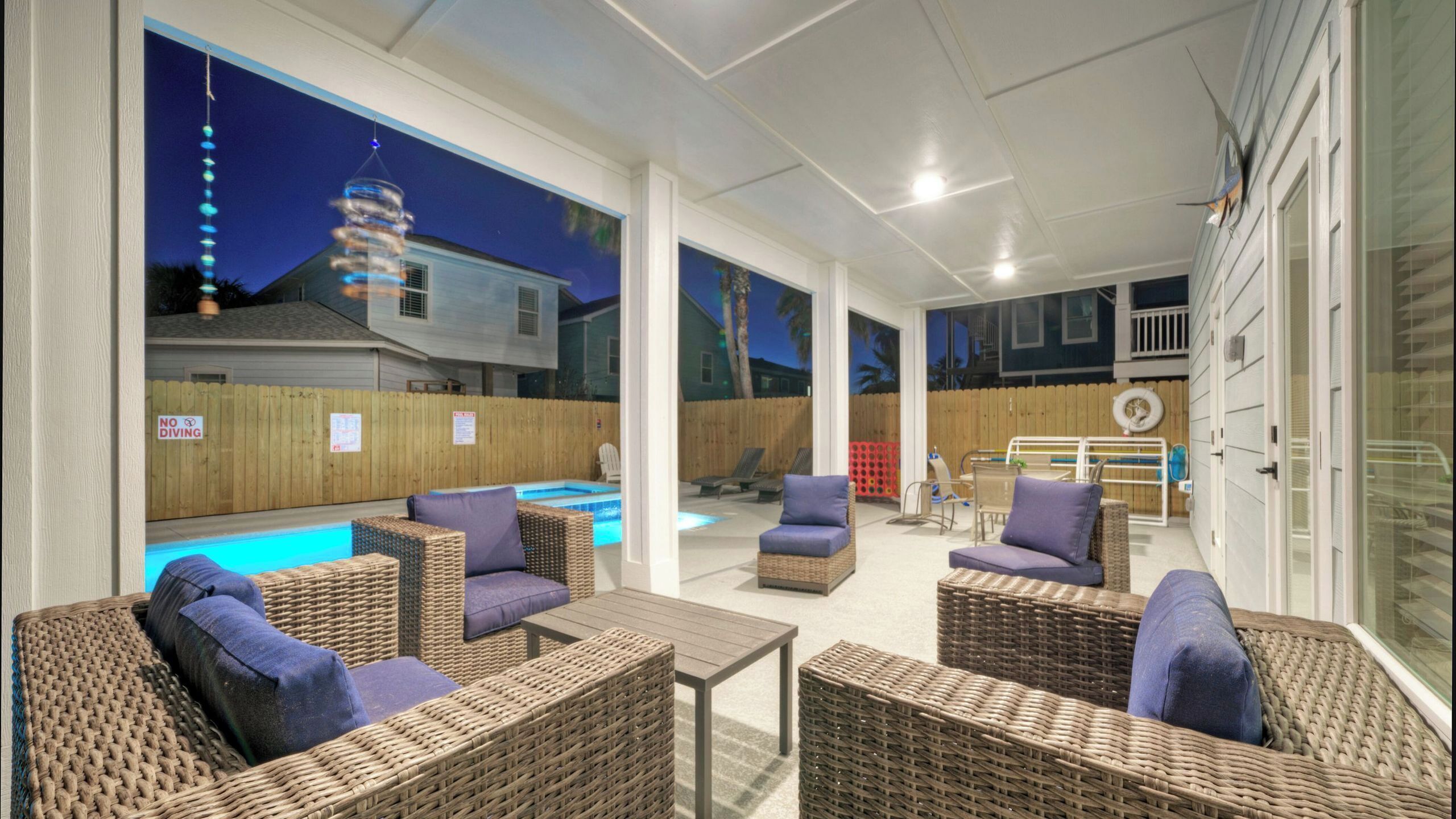 An outdoor patio area with wicker furniture, a pool, and a view of neighboring houses.