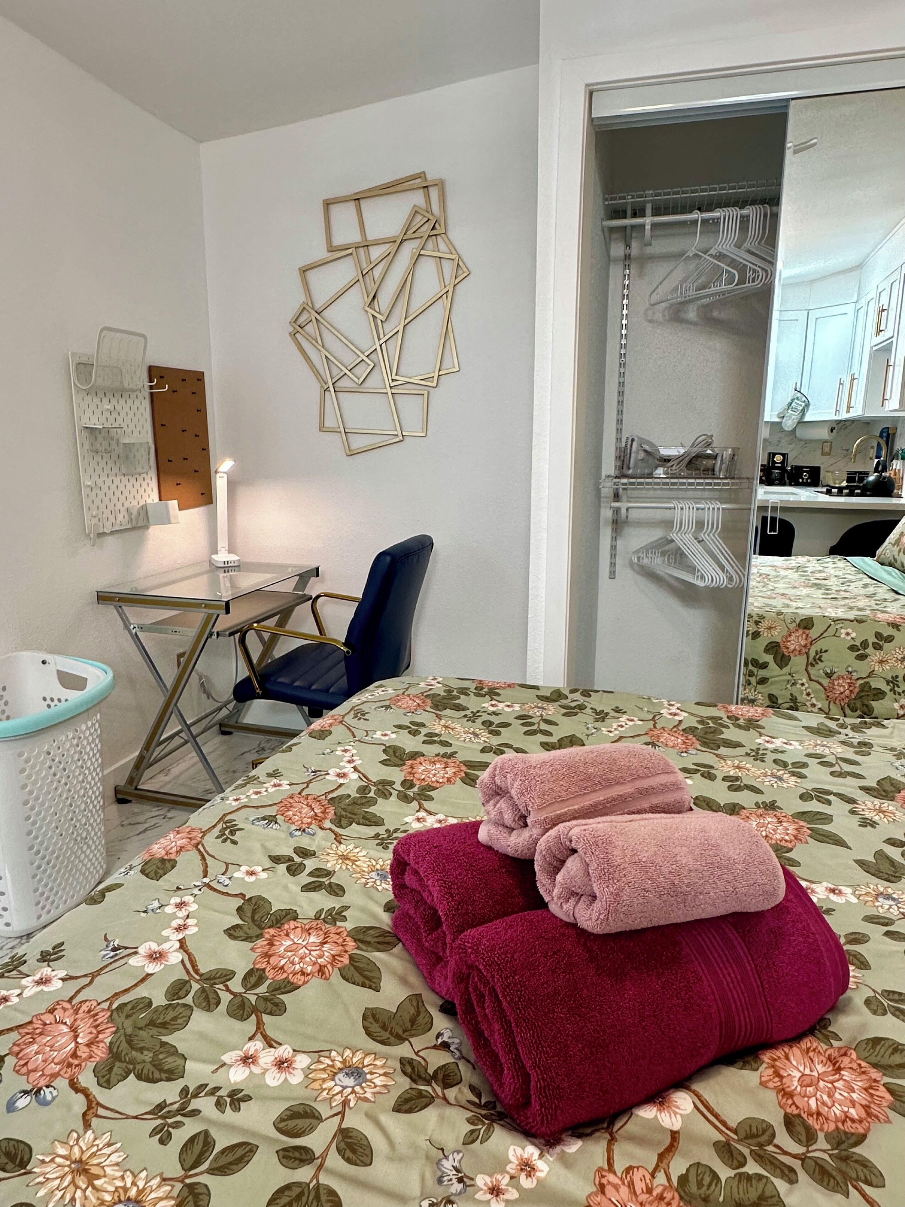 Habitación de hotel con cama, escritorio, silla, espejo y armario.