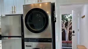 Una cocina con electrodomésticos de acero inoxidable, armarios blancos y piso de mármol.