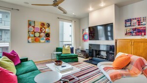 A modern living room with a green sofa, a white armchair, and a striped rug.