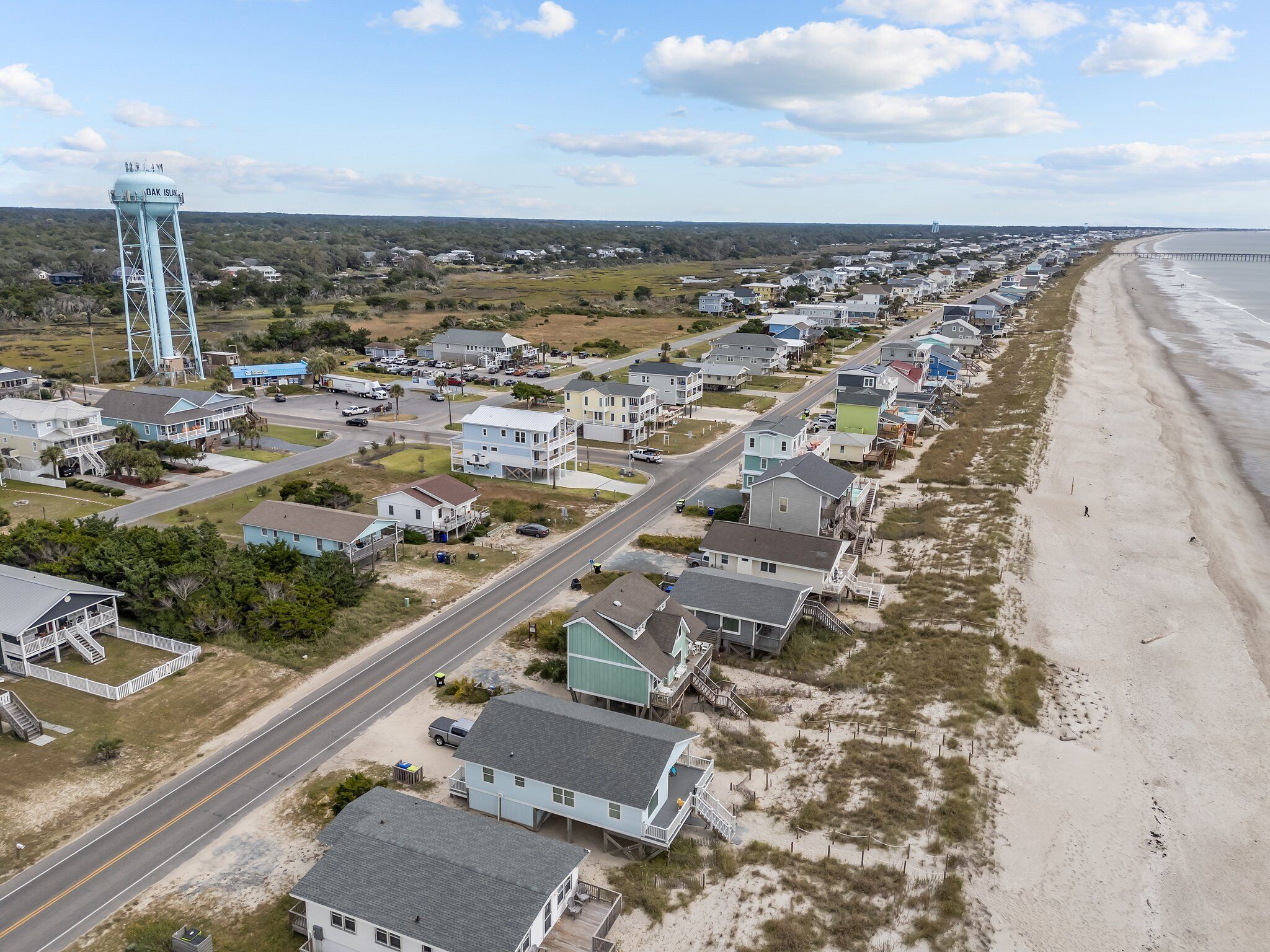 Uma área residencial costeira com casas ao longo da praia, uma estrada e um tanque d'água.