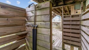 Una ducha exterior de madera con manguera y grifo de metal.