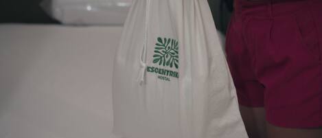 Una bolsa de tela blanca con un logotipo y texto, sostenida por una persona que lleva pantalones cortos rojos.
