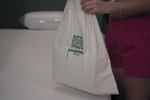 A white tote bag with a logo and text, held by a person wearing red shorts.
