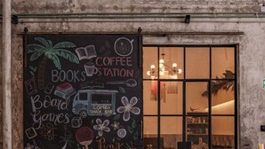 Ein gemütliches Café mit einer Kreidetafel, auf der Kaffee, Bücher, Gesellschaftsspiele und ein Billardtisch angeboten werden.