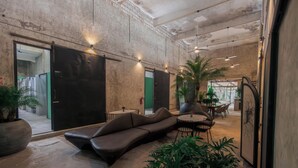 Eine moderne Lobby mit einer gebogenen Couch, runden Tischen und Topfpflanzen.