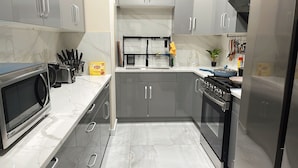 A modern kitchen with grey cabinets, a stainless steel stove, and a microwave.