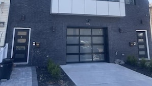 A modern two-story building with a garage entrance, large windows, and a brick facade.