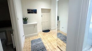 A modern bathroom with a wooden floor, white walls, a mirror, and a small potted plant. - Spacious flat in the East End

 (London)