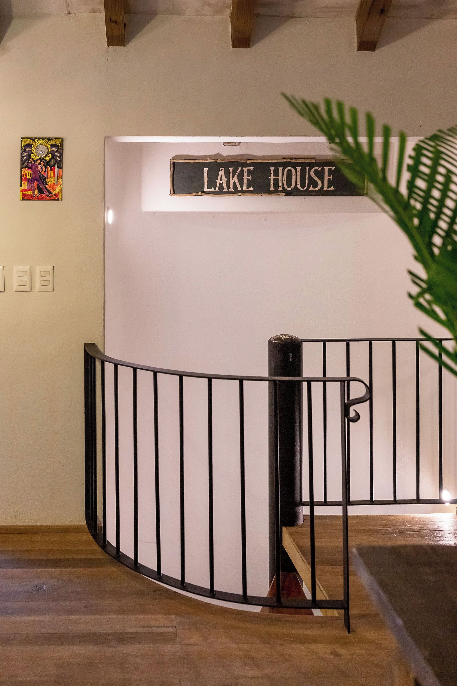 Una escalera con barandilla metálica, piso de madera y un letrero que dice 'LAKE HOUSE'.