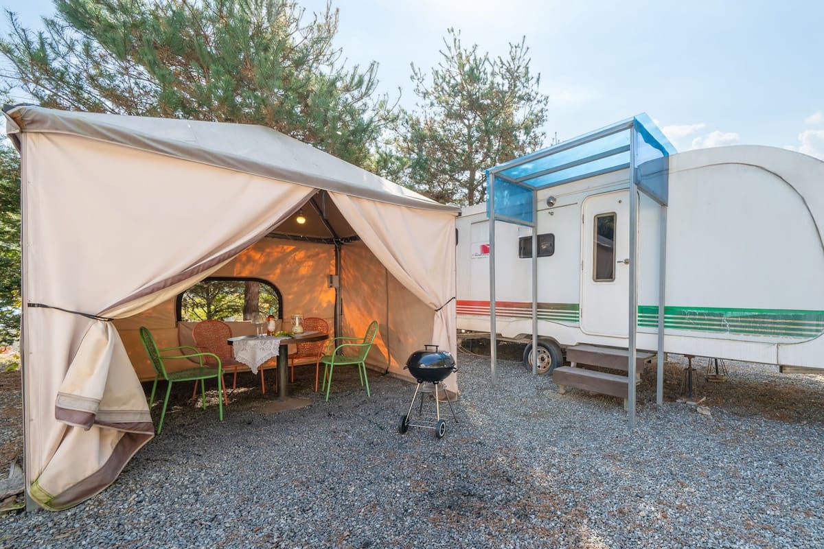 Un terrain de camping avec une tente et une caravane.