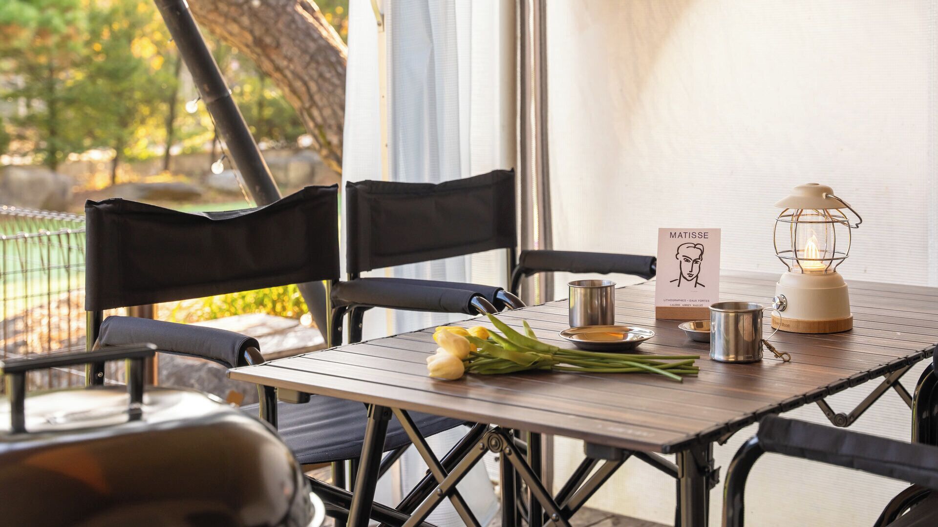 Una mesa con sillas, una vela, un cartel y un farol.