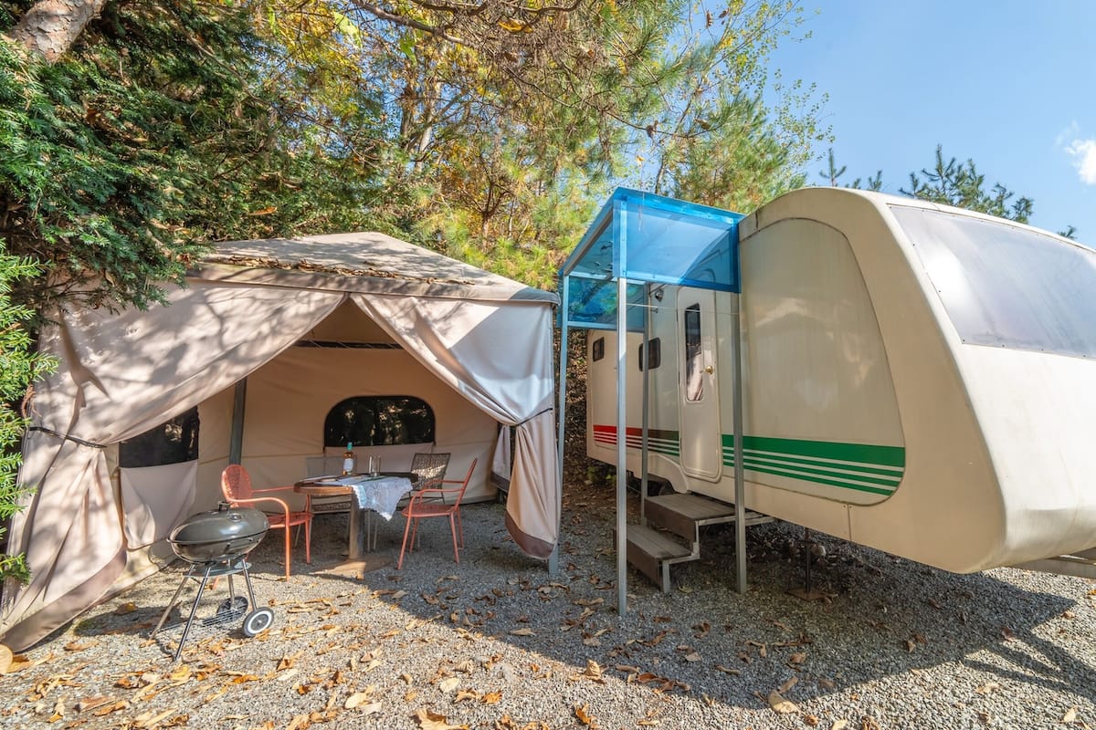 Un véhicule récréatif avec une petite tente et une table installées à proximité.