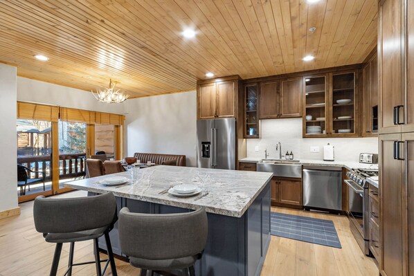 A modern kitchen with wooden cabinets, stainless steel appliances, and a marble island.