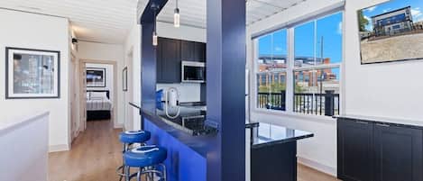 A modern kitchen with a bar area, large windows, and a city view.