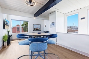A modern room with a round table and blue chairs, large windows, and a ceiling fan.