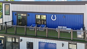 A modern building with a blue exterior, a horseshoe logo, and a balcony with seating.