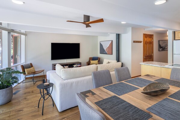 A modern living room with a sofa, a dining table, and a TV.