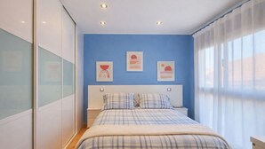 Ein Schlafzimmer mit einem Bett, zwei Nachttischen, einem Fenster mit Vorhängen.