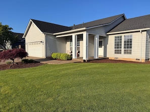 A single-story house with a covered porch, a garage, and a well-maintained lawn. - Charming 3-bedroom Home in Canby (Canby)