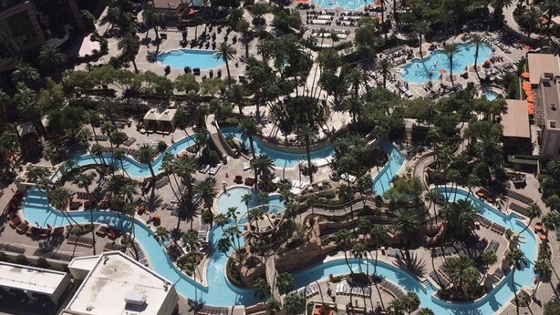 Un vaste espace extérieur doté de plusieurs piscines, entouré de palmiers et de chaises longues.