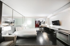 Una habitación de hotel moderna con una cama grande, un escritorio, un televisor y un espejo.