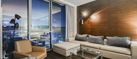 Una sala de estar moderna con un amplio ventanal, un sofá, un sillón y una mesa de centro.
