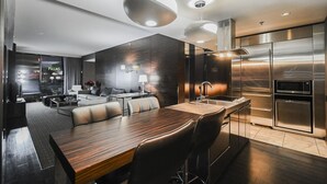 A modern hotel room with a dining area, a kitchen with stainless steel appliances, and a view of the city. - SVS: 1BD Strip View | Jetted Tub | Full Kitchen | Sleeps 4 | Palms Place (Las Vegas)