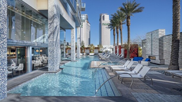 A rooftop pool with lounge chairs, a bar, and a view of the Palm building. - SVS: 1BD Strip View | Jetted Tub | Full Kitchen | Sleeps 4 | Palms Place (Las Vegas)