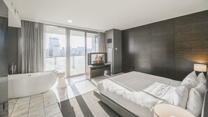 A modern hotel room with a large bed, a bathtub, a flat-screen TV, and a city view. - SVS: 1BD Strip View | Jetted Tub | Full Kitchen | Sleeps 4 | Palms Place (Las Vegas)